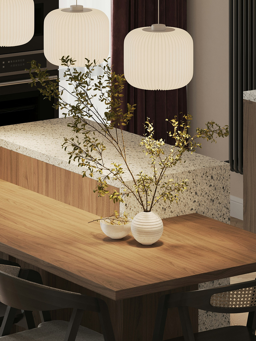 Pendant lights above a terrazzo-topped dining table with foliage in a vase