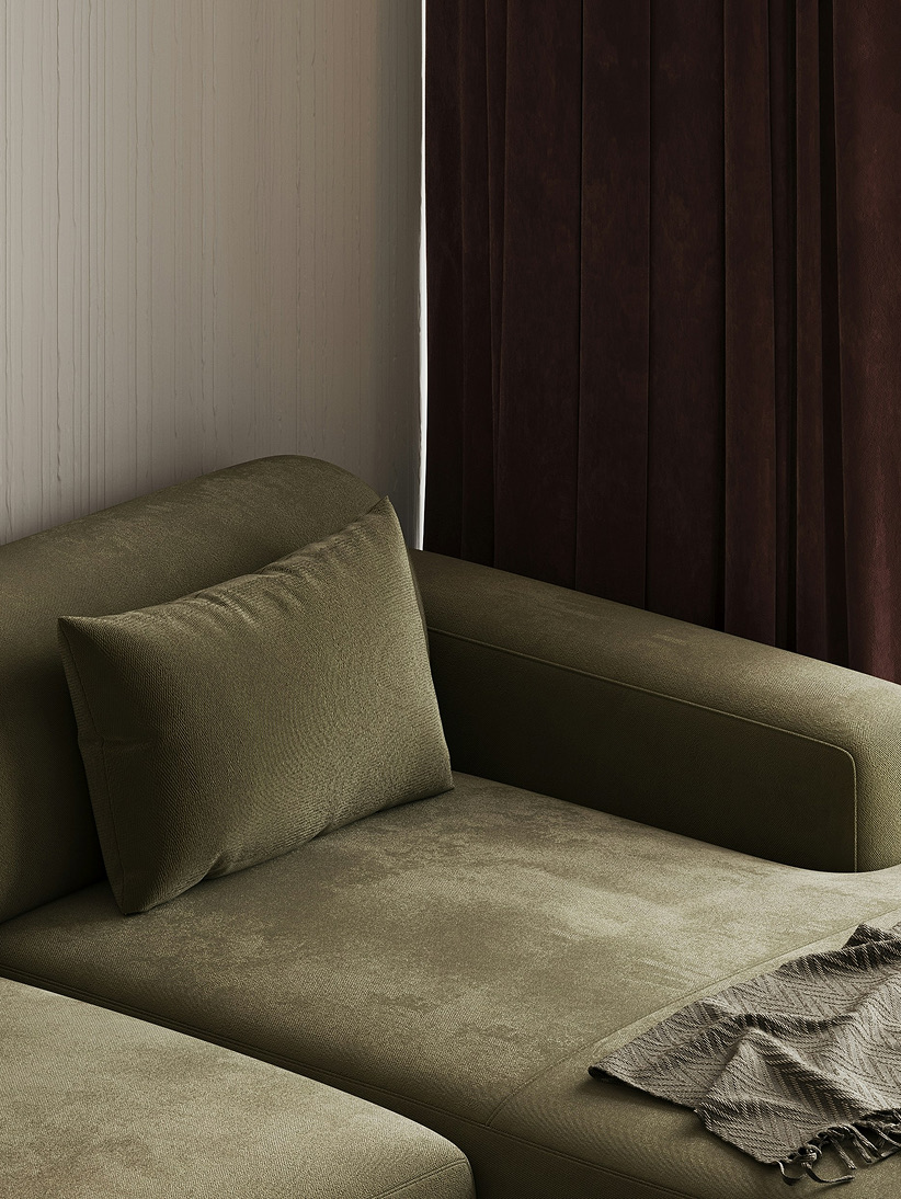A close view of an olive velvet sofa with a folded throw
